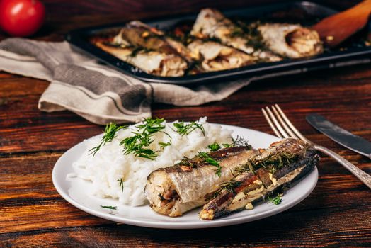 Baked hake carcasses with rice on white plate