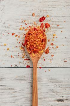 Spoonful of crushed red chili pepper over wooden background