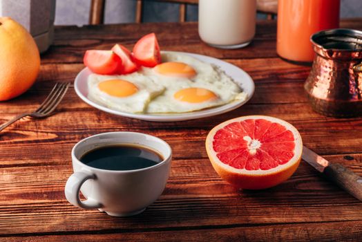 Breakfast with turkish coffee, fried eggs, juice and fruits over wooden table