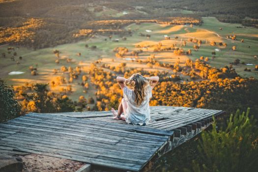 Woman watching the sunset over the mountain valley from rustic broken timber ramp with high views