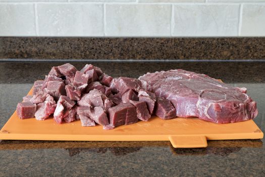a nice lean piece of beef is cut into pieces in the kitchen to prepare a meat dish