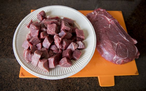 a nice lean piece of beef is cut into pieces in the kitchen to prepare a meat dish