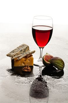 Glass of wine, cheese and fig on a glass background