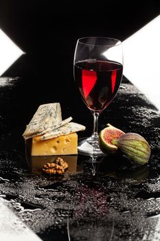 Glass of wine, cheese and fig on a glass background