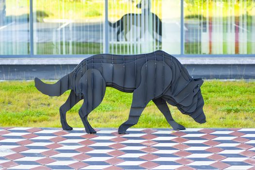 Wolf made of dark-colored metal plates.
