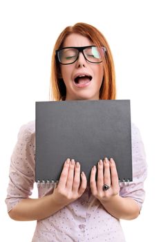 Nerdy young woman with tick glasses with an annoyed and frustrated expression holing a notebook, isolated on white background.