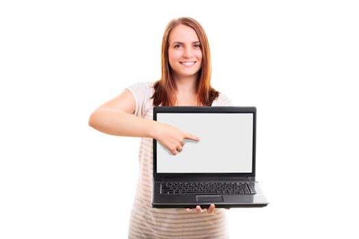 Beautiful young girl standing and pointing at a blank laptop screen, isolated on white background.
