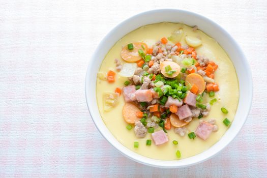 Steamed egg custard cuisine in a white bowl with minced pork, sausage and bacon.  Or Only with egg, water, salt and some sesame oil, you can make this super smooth custard at home. 
