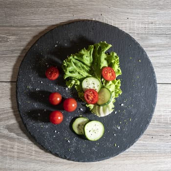 A mixed salad on a black stone surface