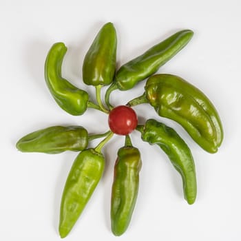 A composition of some green peppers and tomatoes on a white surface