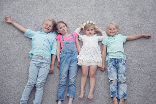 Group of happy kids laying on floor, top view