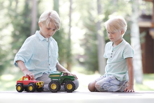 Little brothers playing with toy cars outdoors