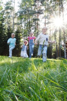 Group of young children running towards camera in park