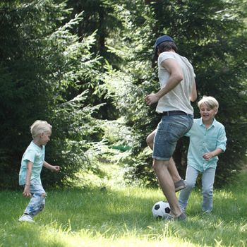 Happy children playing football in summer park