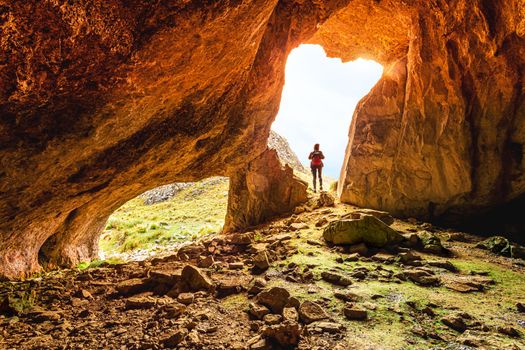 A female exploring caves in Australian wilderness is standing at the cave opening
