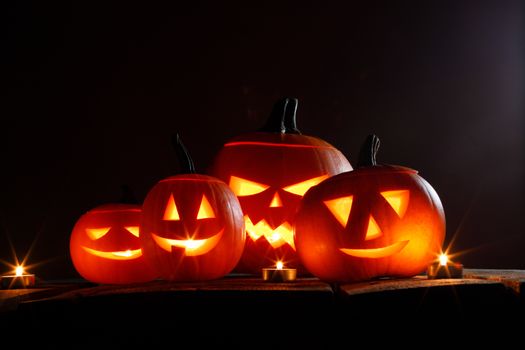 Halloween pumpkin head jack o lantern and candles on wooden background