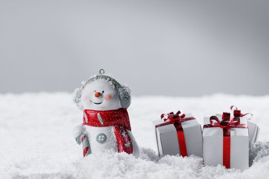 Merry christmas and happy new year greeting card . Happy snowman standing with christmas gifts on gray background