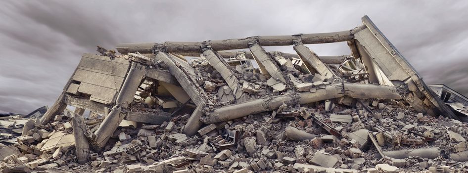 Collapsed concrete industrial building with dramatic sky and another concrete building in background. Disaster scene full of debris, dust and damaged house.