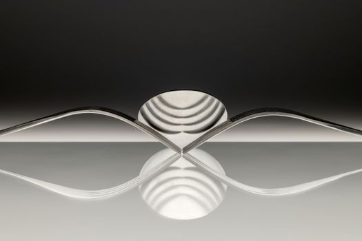 Abstract artistic picture of two forks and a spoon which is reflecting in the surface.
