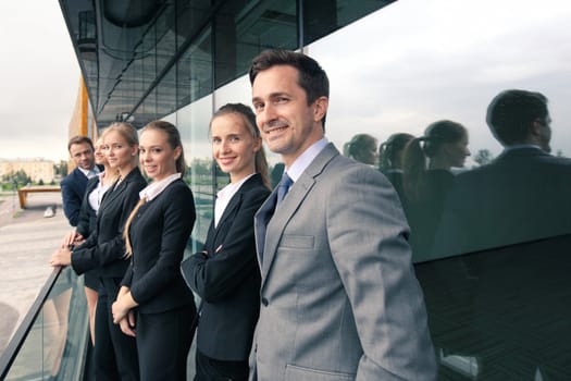 Business people team standing in a row at the balcony of modern office building toned image