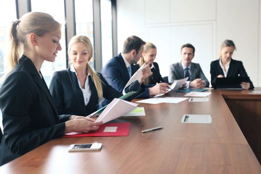 Group of diverse business executives holding a meeting around a table discussing graphs charts showing statistical data analysis