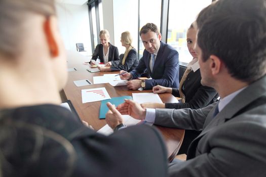 Group of diverse business executives holding a meeting around a table discussing graphs charts showing statistical data analysis