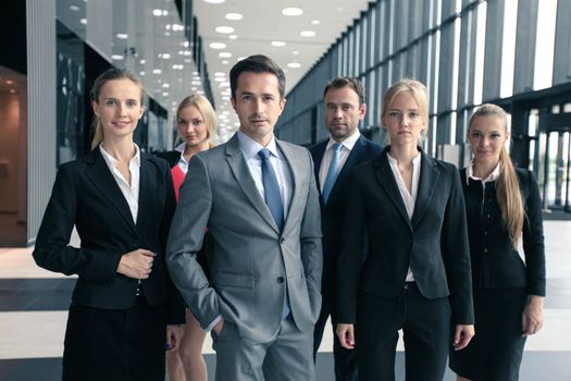 Portrait of group of young excited business people in formal wear standing in office