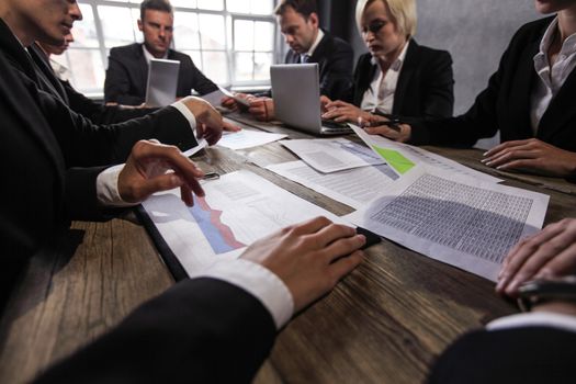 Group of diverse business executives holding a meeting around a table discussing graphs charts showing statistical data analysis