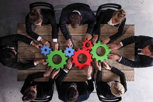 Group Of Business people Joining Together Gears On Table At Workplace