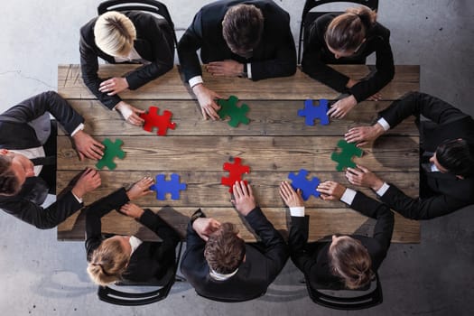 Business people and puzzle on wooden table, teamwork concept