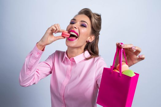 Funny smiling blond woman eating colorful macaroons