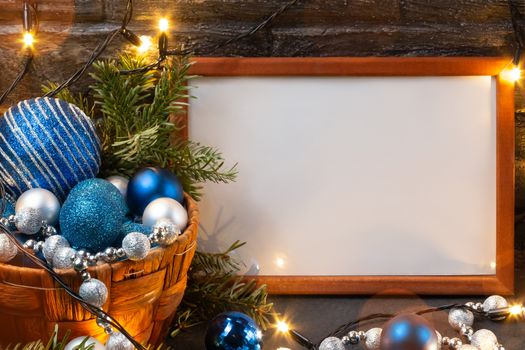 Christmas composition with a wooden frame, lights and decorations in a basket, copy space, place for text.