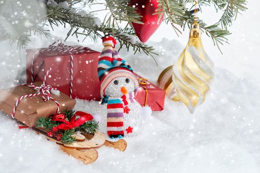 Christmas composition under the Christmas tree - a snowman, boxes with gifts on a sled and other decorations, place for text, copy space.