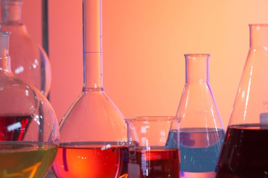 Backlit laboratory test flask containing colorful liquids. Concept of chemistry and research.