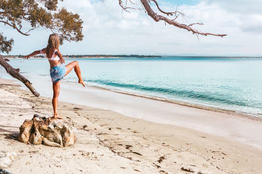 Woman exercising, pilates, yoga on beautiful beach with sandy sea shore