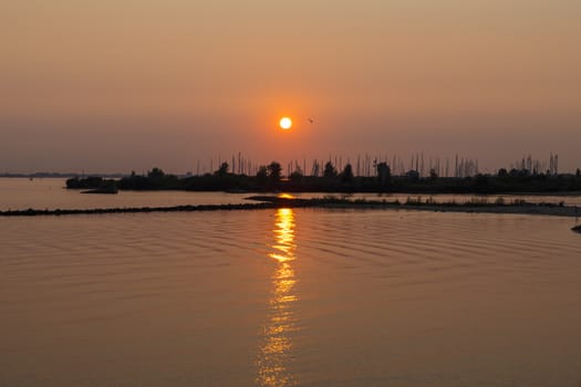 sunset over the harbor of Hellevoetsluis with the boats with masts in silhouette as background and the sky orange red