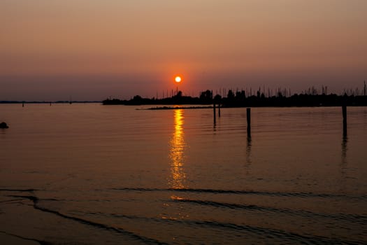 sunset over the harbor of Hellevoetsluis with the boats with masts in silhouette as background and the sky orange red