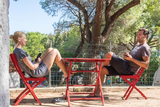 Couple on vacations resting and enjoing in front of mobile home house at camping site in pure nature. Family vacation travel, holiday trip Sardigna, Italy.