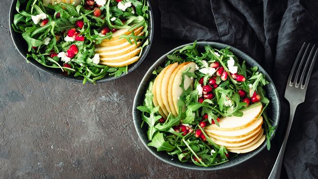 Vegan salad bowl with arugula, pear, pomegranate, coconut crumble or cottage cheese on black background. Vegan breakfast, vegetarian food, diet concept.Top view or flat lay. Copy space for text.Banner