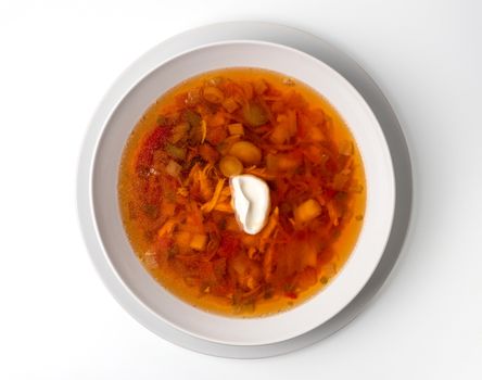 Bowl with chicken, beetroot and other vegetables soup. Perfect bright broth in italian minestrone style, isolated on white. Top view or flat lay.