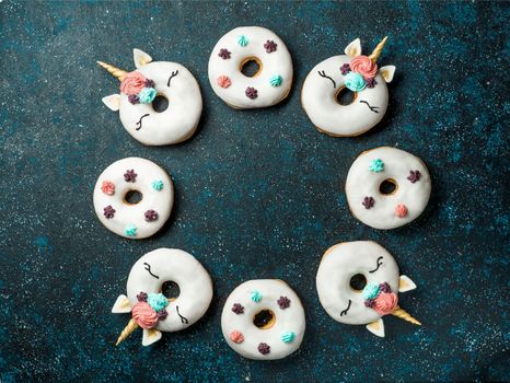 Unicorn donuts over dark background. Trendy donut unicorn with white glaze in circle shape. Top view or flat lay. Copy space for text.