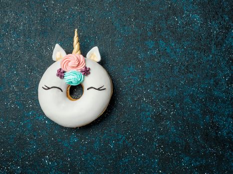 Unicorn donut over dark background. Trendy donut unicorn with white glaze. Top view or flat lay. Copy space for text.