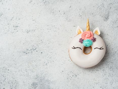 Unicorn donut over gray cement background. Trendy donut unicorn with white glaze. Top view or flat lay. Copy space for text.