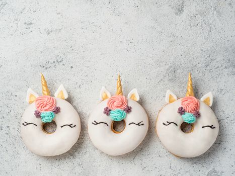 Unicorn donuts over gray cement background. Trendy donut unicorn with white glaze. Top view or flat lay. Copy space for text.