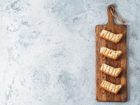caramelized cheesecake slices on wooden cuttingboard. Cheesecake on gray cement background with copy space for text. Top view or flat lay.