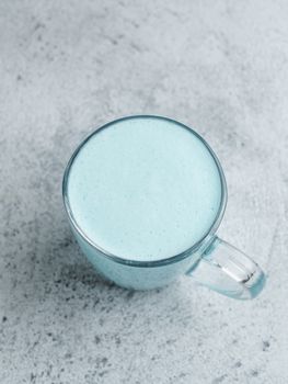 Trendy drink: Blue latte. Top view of hot butterfly pea latte or blue spirulina latte on gray cement textured background. Copy space for text. Top view or flat lay.