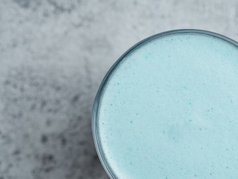 Trendy drink: Blue latte. Close up view of hot butterfly pea latte or blue spirulina latte on gray cement textured background. Copy space for text. Top view or flat lay.