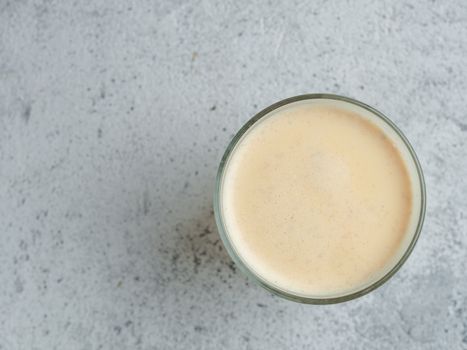 Healthy drink golden turmeric latte in glass cup. Yellow homemade latte on gray background. Detox turmeric tea latte. Copyspace for text Top view or flat lay.