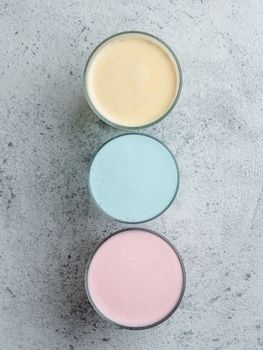 Trendy drinks: Blue, yellow and pink latte. Top view of hot butterfly pea or blue spirulina latte, yellow or gold turmeric latte and pink beetroot latte on gray cement background. Copy space for text