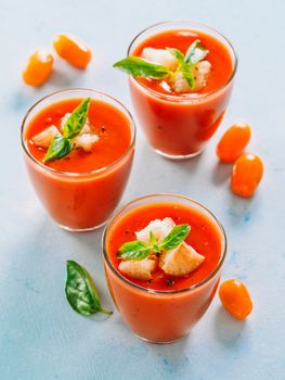 Delicious gaspacho soup in glass. Traditional spanish cold soup puree gaspacho or gazpacho on gray cement background. View from above or top view or flat lay. Vertical.
